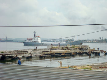 People on pier by sea against sky