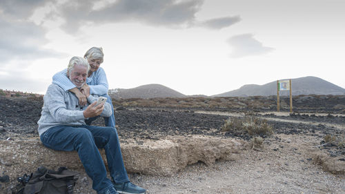 Senior couple using smart phone against sky