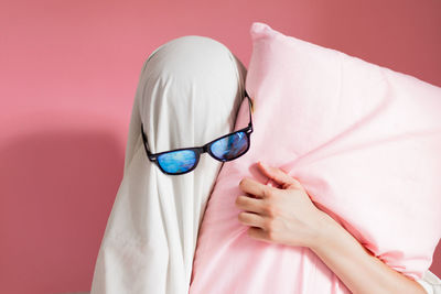 Close-up of woman wearing eyeglasses against pink background