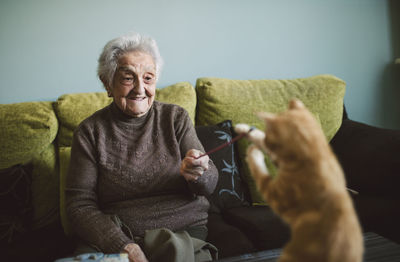 Smiling senior woman playing with her kitten at home