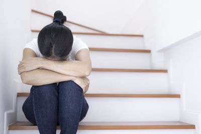 Rear view of woman sitting on staircase at home