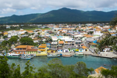 Tilt shift image of town by river against mountains