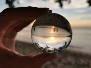 Close-up of hand holding crystal ball at beach