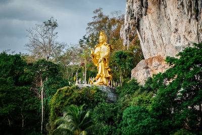 Low angle view of golden statue amidst trees