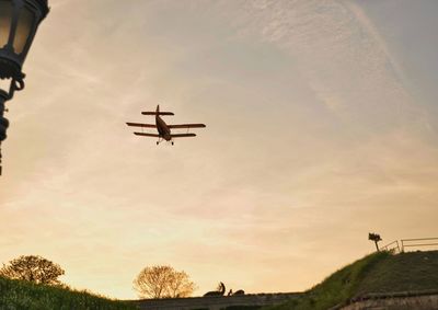 Low angle view of airplane flying against sky during sunset