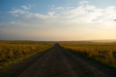 Road amidst field against sky