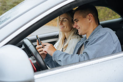 A young couple on a road trip looking at a map on their phone in a navigator.