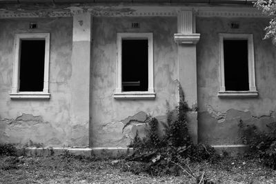 Three windows in an abandoned building in black and white