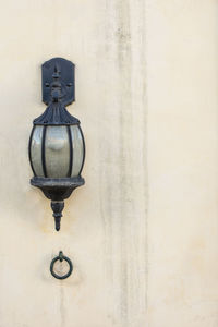 Close-up of electric lamp hanging against wall