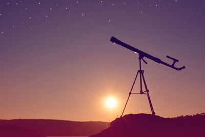 Silhouette telescope against sky at night