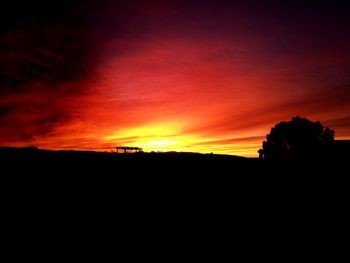 Silhouette landscape against orange sky