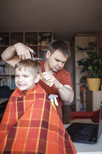 Rear view of man and woman using laptop at home