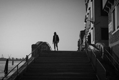 Rear view of man walking on staircase against sky
