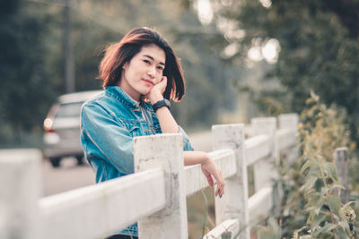 Young woman looking away while standing by railing