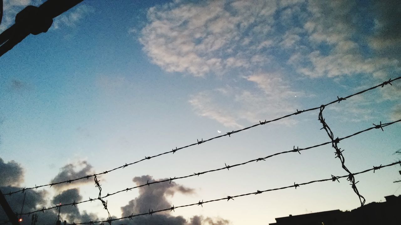 sky, fence, low angle view, silhouette, protection, safety, cloud - sky, security, chainlink fence, metal, cloud, nature, railing, built structure, outdoors, day, no people, branch, tree, barbed wire