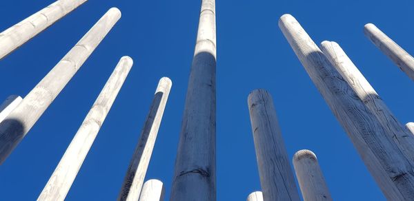 Low angle view of poles against clear blue sky