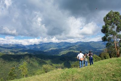 Rear view of people walking on mountain against sky