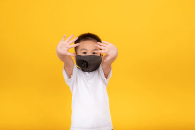 Full length of boy standing against yellow background