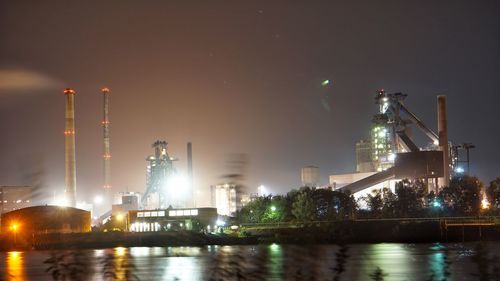 Illuminated factory against sky at night