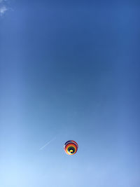 Low angle view of balloons flying against blue sky