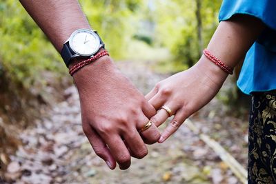 Cropped image of couple holding hands at forest