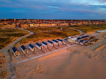 Aerial view of coastal town at sunset row of beach cabins with decks, sandy beach, grassy dunes