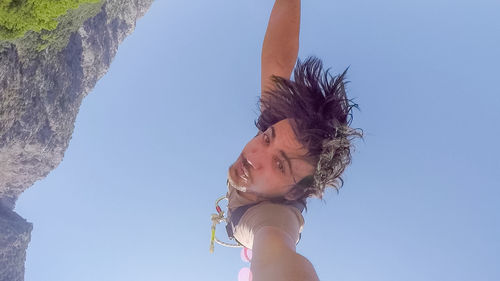 Low angle portrait of woman against clear sky