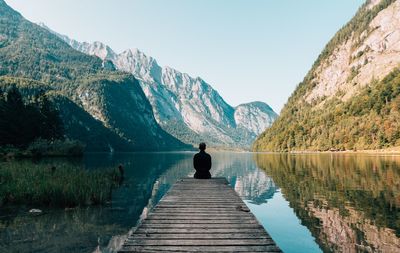 Rear view of man looking at lake against mountain