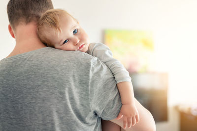 Rear view of father holding son at home