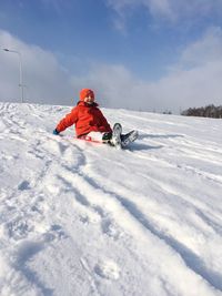 Low angle view of boy sliding on snow against sky