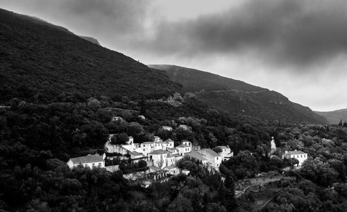 Houses on hill against cloudy sky
