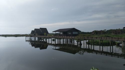 Stilt houses in lake against sky