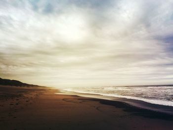 Scenic view of beach against cloudy sky