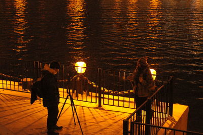 Rear view of people walking on illuminated street at night