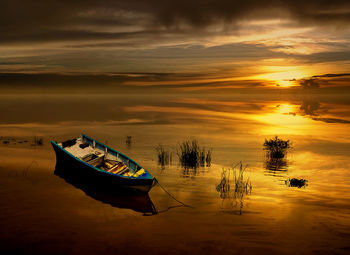 Boat moored in sea against sky during sunset