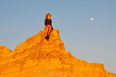 Low angle view of young woman standing on landscape