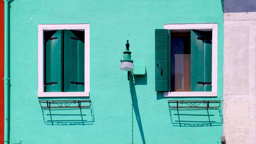 Two windows house in burano on green wall building architecture with lamp, venice, italy