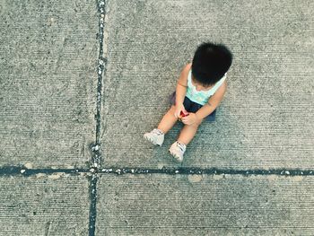 Directly above shot of child sitting on walkway