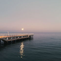 Pier over sea against clear sky during sunset