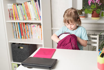 Girl takes out books and stationery from her backpack. preparation for school. back to school.