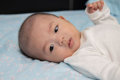 Portrait of cute baby lying on bed