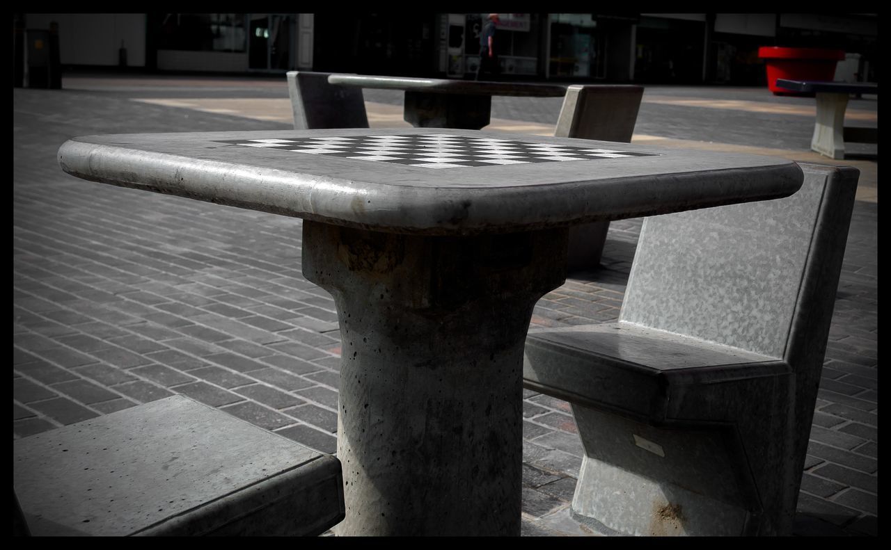 CLOSE-UP OF EMPTY CHAIRS AND TABLE BY BENCH