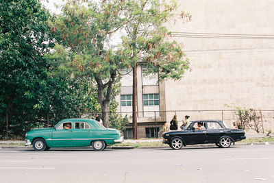 Vintage car on road against trees in city