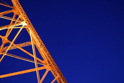 Low angle view of illuminated bridge against clear blue sky