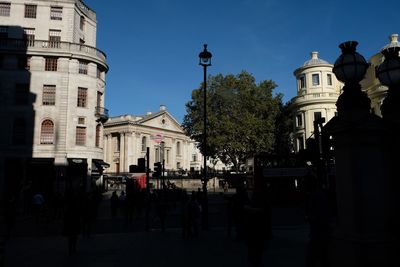 Street amidst buildings in city against blue sky