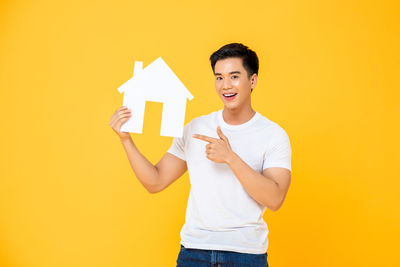 Happy boy standing against yellow background