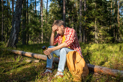 Side view of man sitting in forest