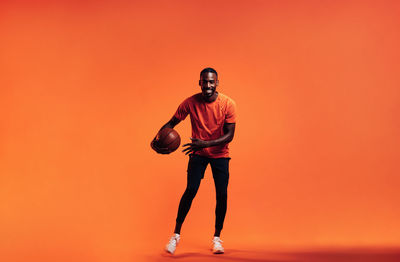 Full length of man standing against orange background