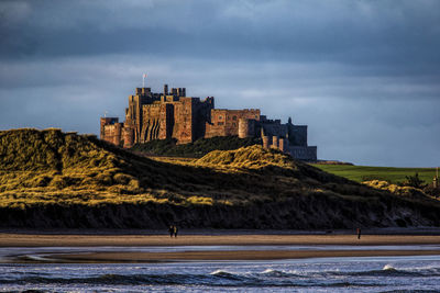 Buildings by sea against sky