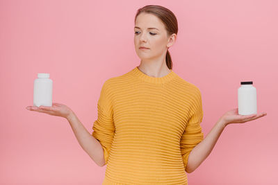 Mid adult woman looking away while standing against gray background